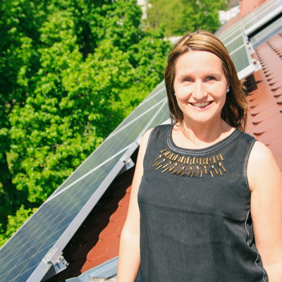 Frau auf einem Dach vor einem Solarmodul