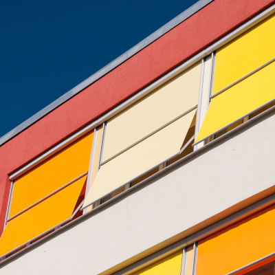 Eine Hausfassade mit farbenfrohem Sonnenschutz.