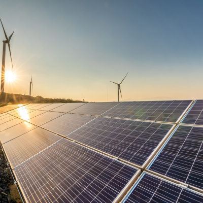 Photovoltaikanlage auf Freifläche mit Windkraft im Hintergrund