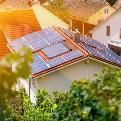 Ein mit Photovoltaik ausgestattetes Einfamilienhaus, umgeben von weiteren Häusern.