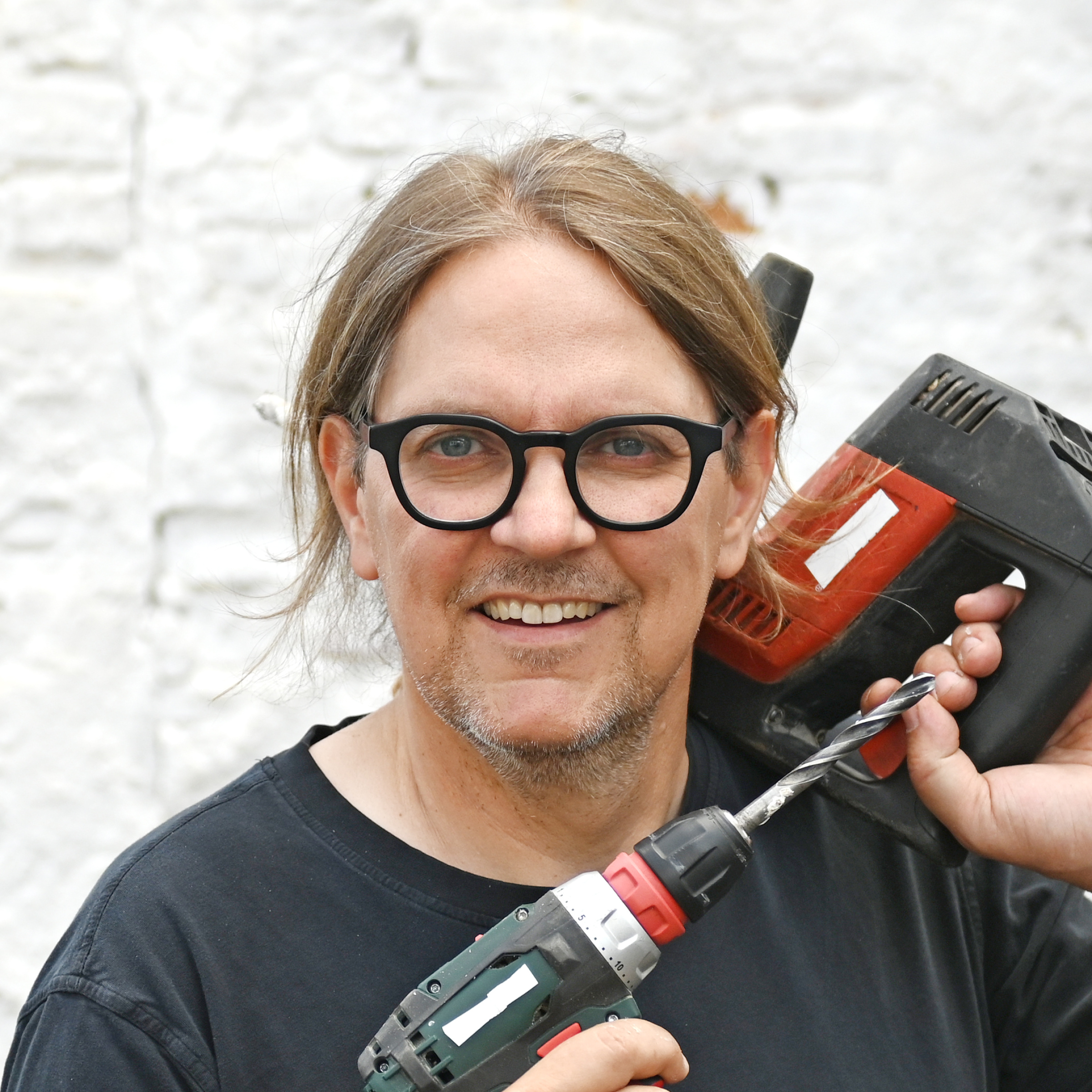 Portrait Carsten Herbert mit Bohrmaschine und Klebepistole.