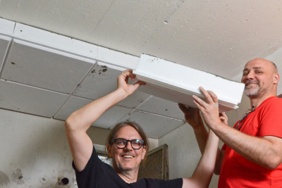 Zwei Männer bringen einen Dämmplatte an der Kellerdecke an.