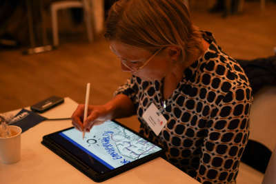 Frau zeichnet mit einem Stift auf ein Grafiktablett.