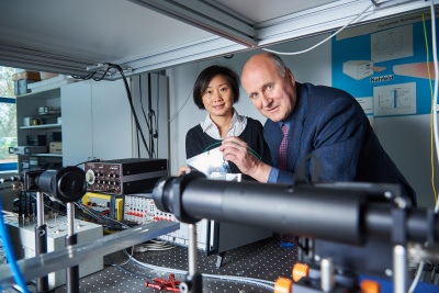 Ein Mann und eine Frau stehen vor einer Versuchsanordnung mit elektronischen Geräten.