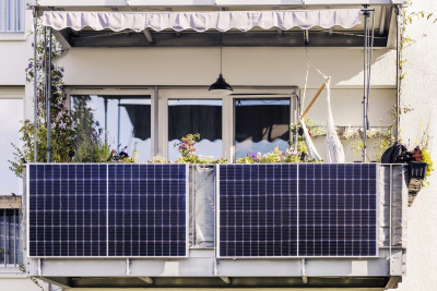 Zwei Steckersolargeräte die an einem Balkon angebracht sind.