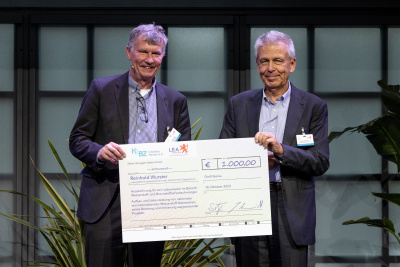 Zwei Männer halten einen großen Scheck über 1.000 Euro für Reinhold Wurster.
