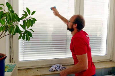 Das Bild zeigt, wie ein Mann eine Fensterscheibe von innen putzt