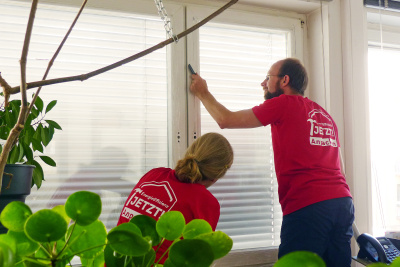 Zwei Männer bringen eine Fensterfolie an.