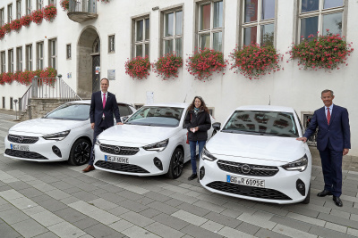 Mitarbeitende der Stadt Rüsselsheim stehen neben drei neuen E-Autos in weiß vor einem Gebäude.