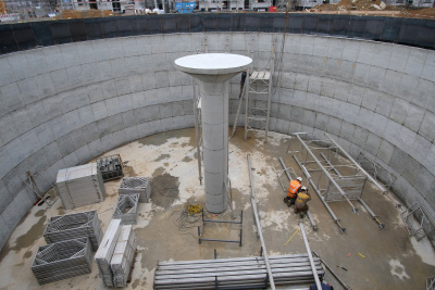 Der Eisspeicher in der Ökosiedlung in Friedrichsdorf im Bau. Am Boden hocken zwei Arbeiter mit Helmen vor Eisenteilen.