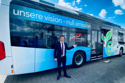 Elektrobus der Gemeinde Maintal steht auf einem Platz und wird betankt. Vor dem Bus steht ein Mann im Anzug.