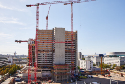 Baustelle mit mehrstöckigen Gebäude und mehreren Baukränen.