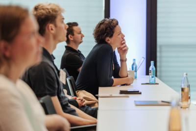 Menschen sitzen am Tisch und lauschen der Veranstaltung.