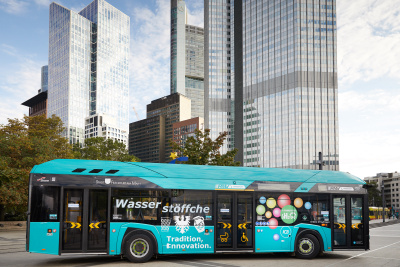 Brennstoffzellenbusse: Bus in türkis mit der Aufschrift "Wasserstöffche" steht vor Geschäftshochhäusern in Frankfurt am Main.