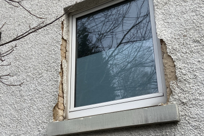 Altes Fenster umgeben von schadhaften Putz