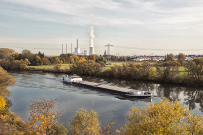 Das Kohlekraftwerk in Großkrotzenburg mit dem Main und einem Lastschiff im Vordergrund.