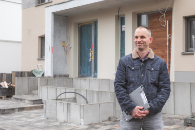 Energieeffizienzberater steht mit Klemmbrett vor einem Neubau.