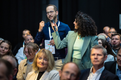 Person aus dem Publikum stellt eine Frage ans Podium