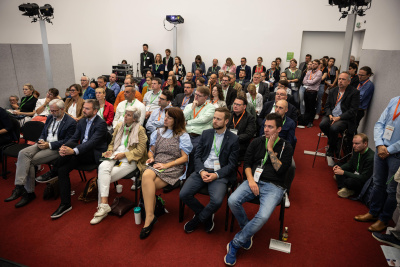 Zukunftsforum Energie & Klima: Sitzende und stehende Zuschauer in einem Vortragssaal mit rotem Teppich.
