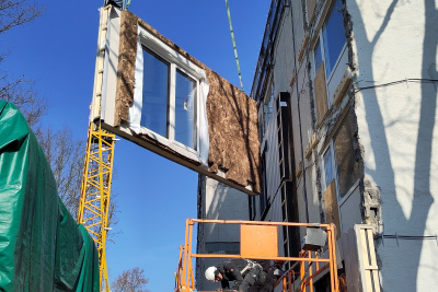 Ein Teil einer Fassade hängt an einem Kran