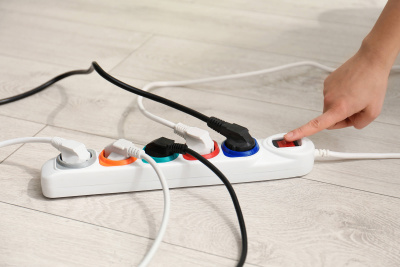 Eine Hand betätigt den An-/Aus-Schalter auf einer Steckerleiste