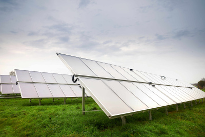 Mehrere Solarkollektoren sind in Reihen auf einer Wiese angeordnet.