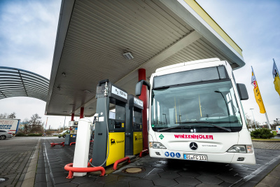 Bus steht an einer überdachten Wasserstofftankstelle.