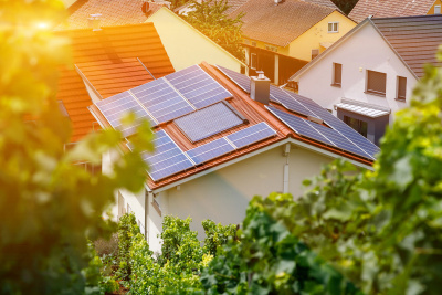 Ein mit Photovoltaik ausgestattetes Einfamilienhaus, umgeben von weiteren Häusern.