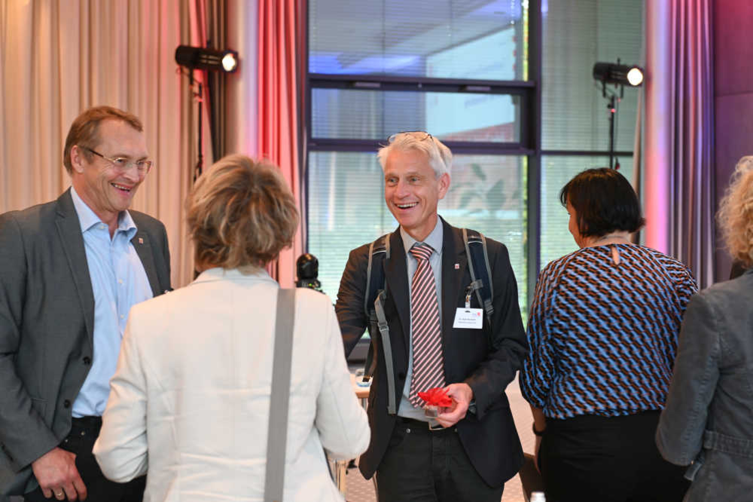 Geothermie-Forum 2022: Begrüßung Mehrere Frauen und Männer stehen in einem Sitzungssaal zusammen und begrüßen sich lächelnd.