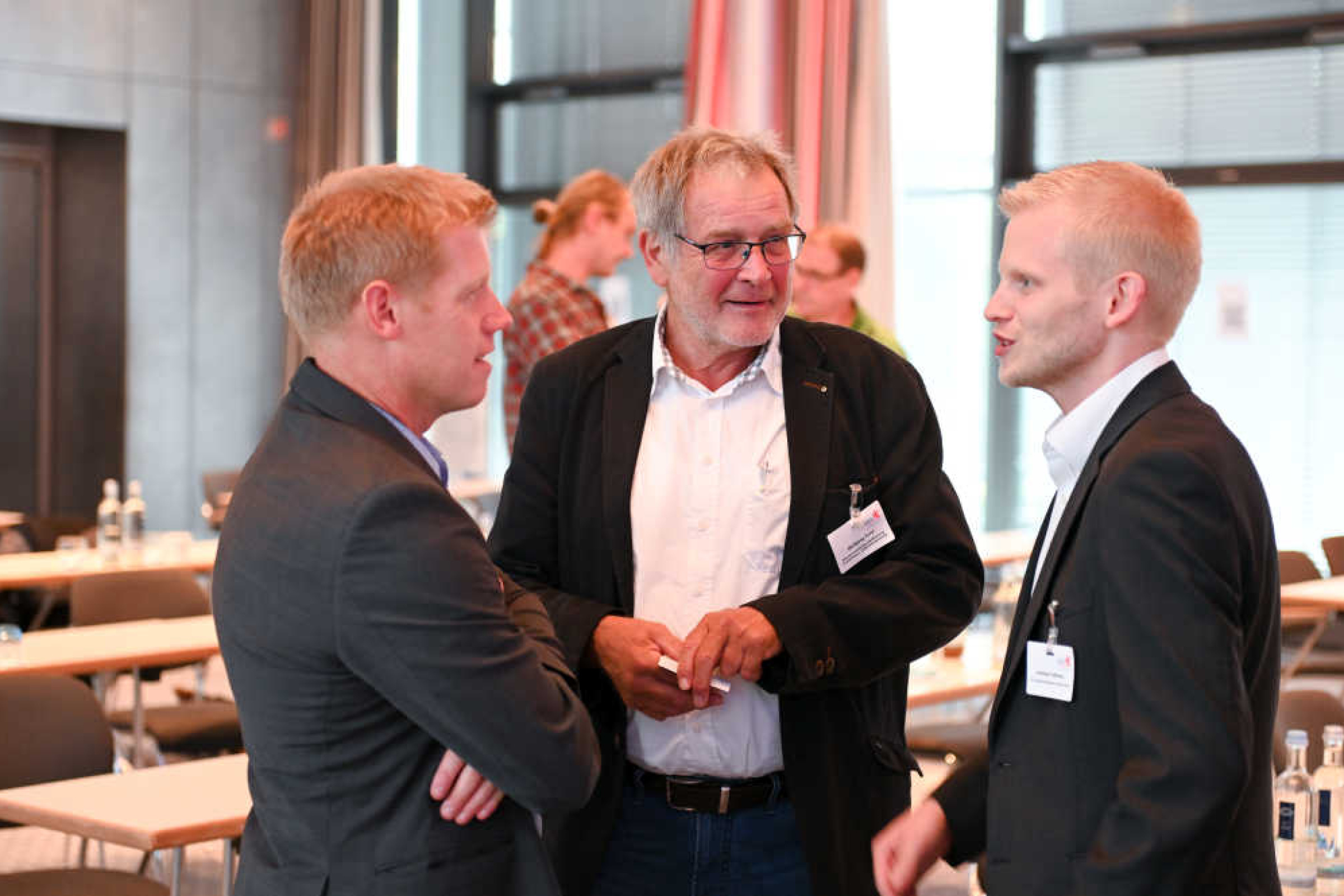 Geothermie-Forum 2022: Dreiergespräch Drei Männer stehen in einem Sitzungssaal zusammen und sprechen miteinander.