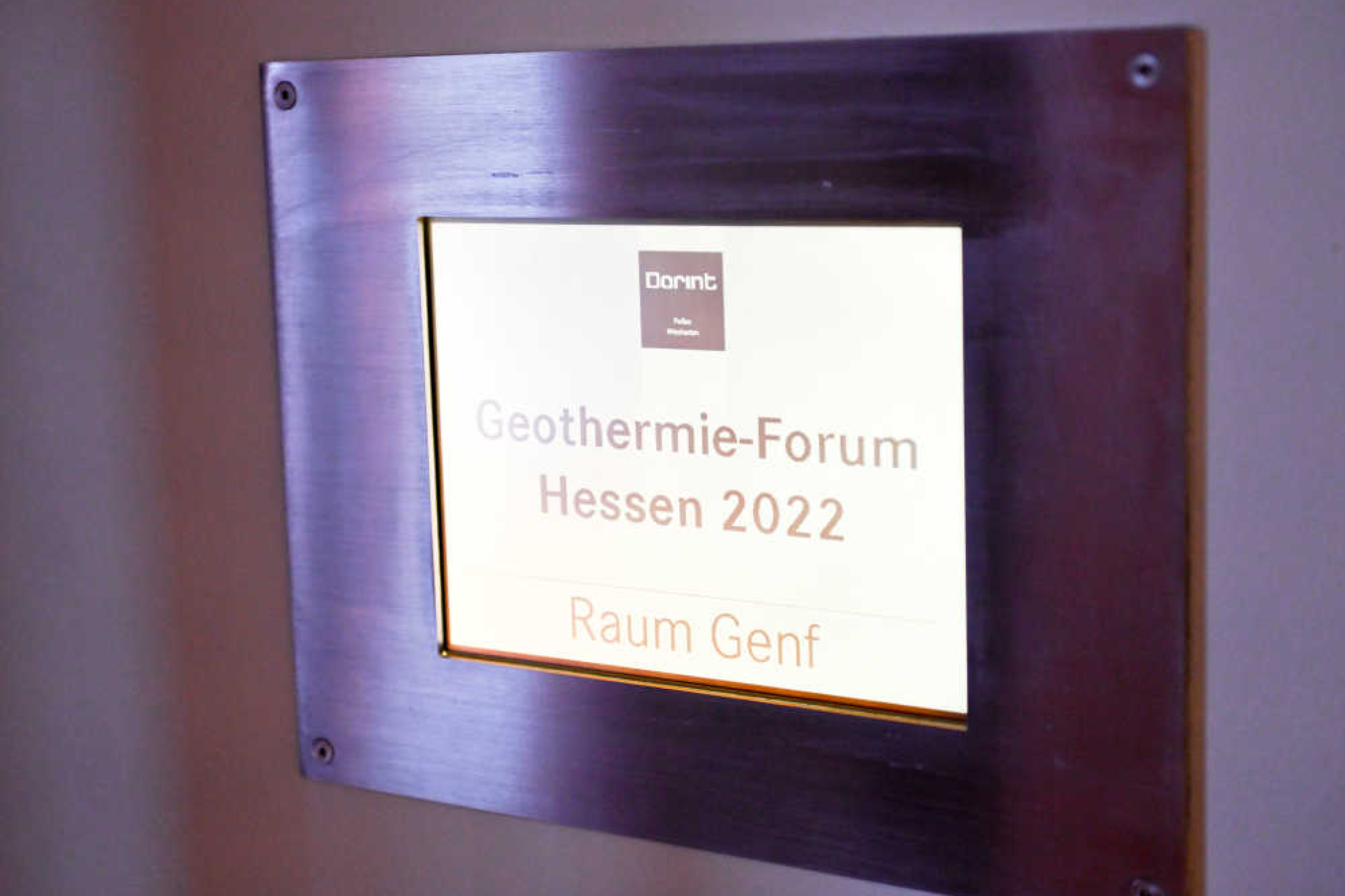 Schild mit dunklem Rahmen, Aufschrift: "Dorint – Geothermie-Forum Hessen 2022, Raum Genf"