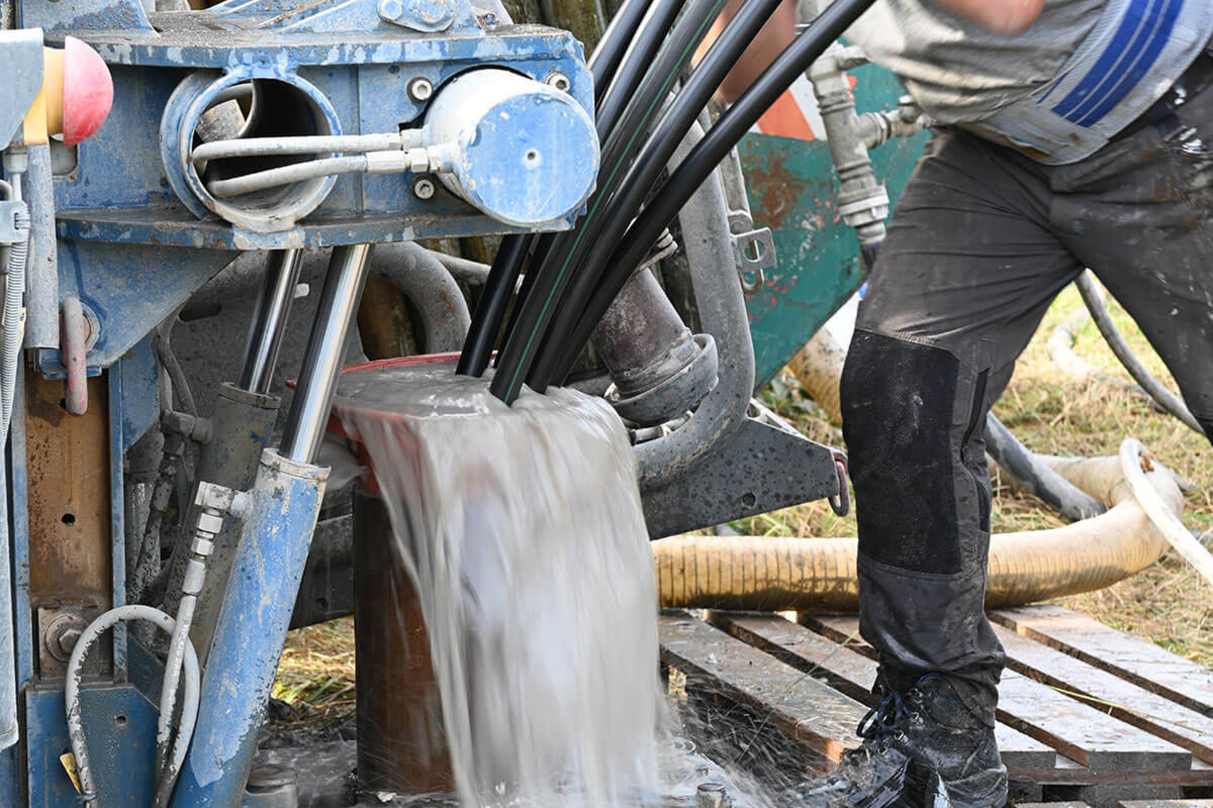 Geothermie: Probebohrung Stockstadt 14.09.2021, Arbeiter führt Schläuche in Bohröffnung ein.