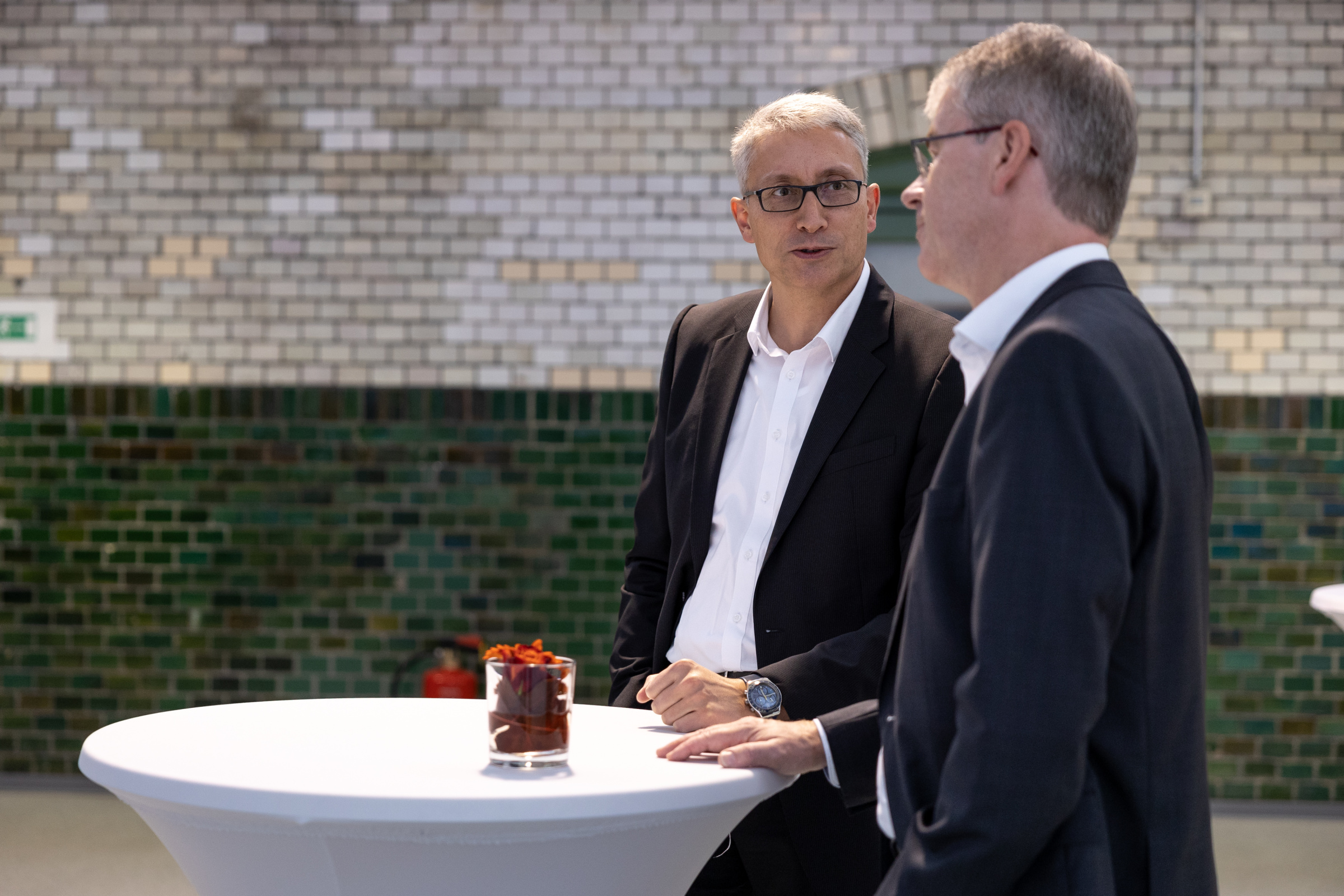 Brennstoffzellenforum 2022 Zwei Männer in Anzügen stehen um einen weißen Stehtisch.