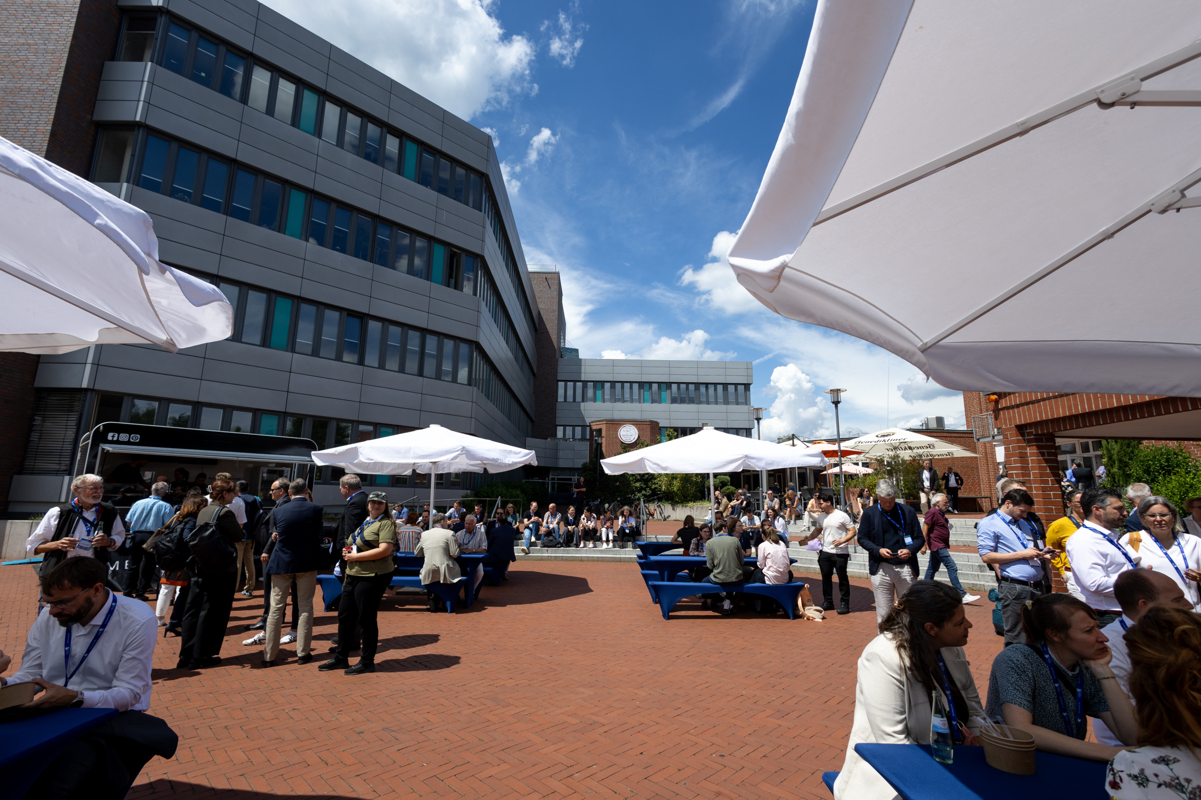 Große Schirme, Sitzbänke und Foodtrucks draußen vor dem Gebäude