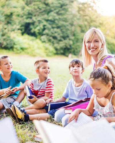 Eine Lehrerin unterrichtet eine Gruppe Kinder im Freien