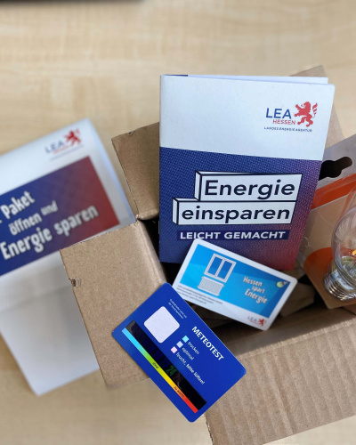 Das Foto zeigt den Inhalt des hessischen Energieeinsparpakets: Eine Broschüre, eine LED-Lampe sowie ein Thermo-Hygrometer