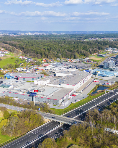 Gewerbegebiet aus Vogelperspektive mit Autobahnzubringer, Parkplätzen und verschiedenen Industriegebäuden