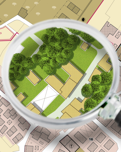 Imaginärer Stadtplan mit Gebäuden und Straßen. eine Lupe unter der man die Stadt mit grüner Bepflanzung sieht
