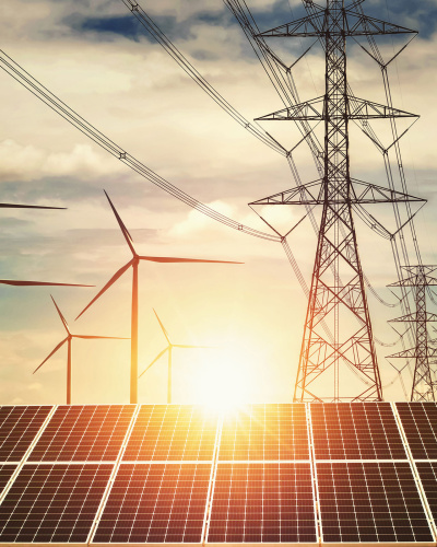 Windr&auml;der, Strom-&Uuml;berlandleitungsmasten und Solarkollektoren vor untergehender Sonne.