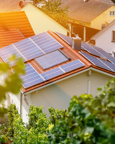 Ein mit Photovoltaik ausgestattetes Einfamilienhaus, umgeben von weiteren Häusern.