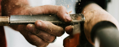 Detailansicht Hände die Holz an Maschine bearbeiten