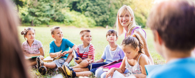 Eine Lehrerin unterrichtet eine Gruppe Kinder im Freien