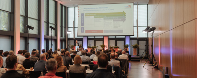 Menschen in Saal vor einer Leinwand