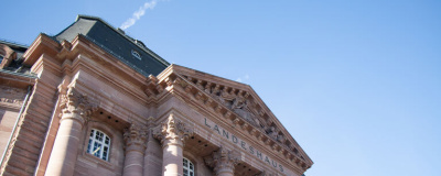 Gebäude mit Säulenportikus vor einem blauen Himmel.