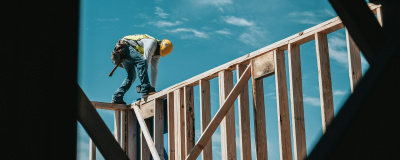Mann in Arbeitsmontur arbeitet an Holzdach