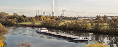 Das Kohlekraftwerk in Großkrotzenburg mit dem Main und einem Lastschiff im Vordergrund.