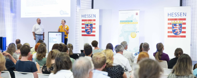 Personen im Publikum hören einen Vortrag auf der Hauptbühne bei der Konferenz Klima Kommunal 2023.