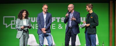 Moderatoren Duo auf der Bühne mit den Geschäftsführern von der LEA Hessen und deENet e.V.