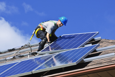 Ein Mann montiert Solarpanele auf einem Dach.