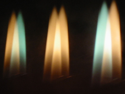 Das Foto zeigt drei Flammen, die man sieht, wenn man ein Feuerzeug vor eine dreifach verglaste Scheibe hält.